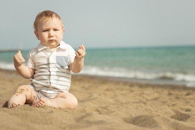 Een jongetje zittend op een zand aan de kust