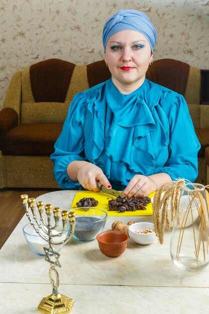 Een Joodse vrouw in een traditionele hoofdtooi aan een tafel waar een menora zich voorbereidt