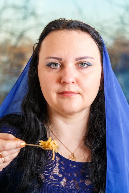 Foto een joodse vrouw met haar hoofd bedekt met een blauwe cape at de pascha seder tafel eet haroset