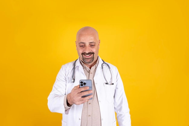 Een kale man in een witte laboratoriumjas houdt een telefoon vast met een stethoscoop in zijn linkerhand
