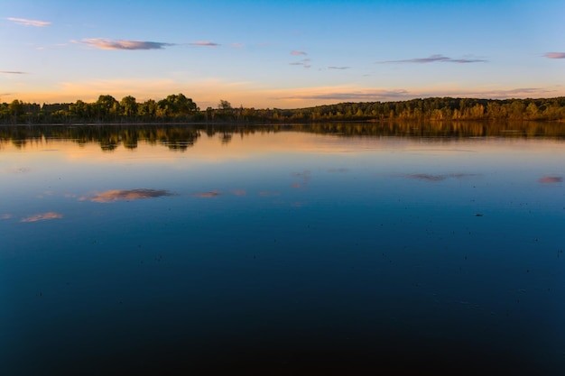 Een kalm meer met een blauwe lucht en wolken op de achtergrond.