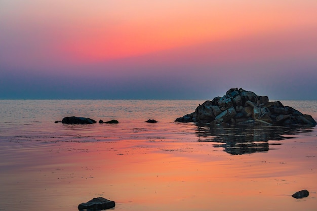 Een kalme zee met een zonsonderganghemel en de zon door de wolken boven ons Meditatie oceaan en lucht Kalm zeegezicht De horizon boven het water