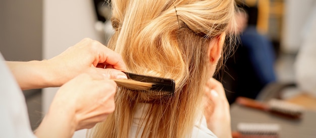 Een kapper kamt vrouwelijke hairstyling in een kappers-schoonheidssalon.