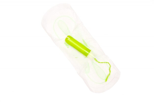 Een katoenen tampon met groene applicartor op maandverband op wit wordt geïsoleerd.