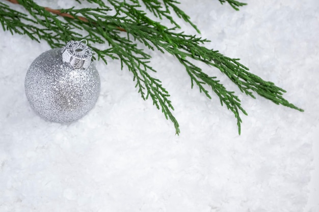 Een kerstbal op de kerstboom ligt op een tak op een witte sneeuw