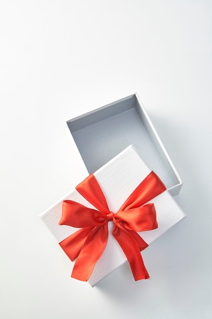 Een kerstcadeau in wit inpakpapier en rode linten