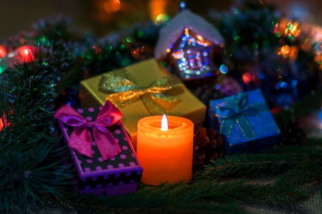 Een kerstkaars rond dozen met cadeautjes van de kerstman op de achtergrond van de bokeh