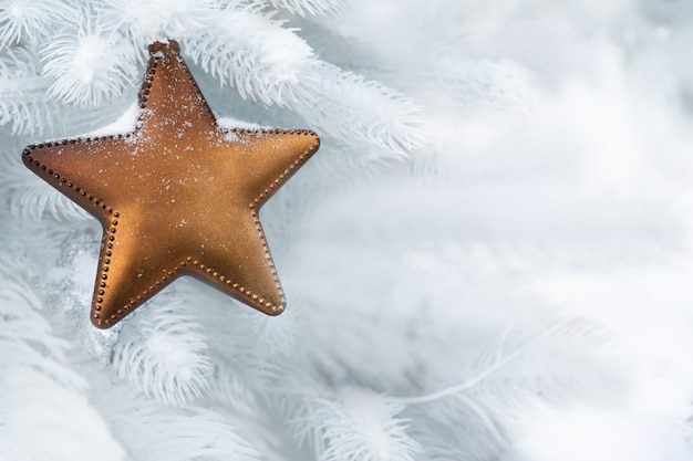 Een kerstster hangt aan een sneeuwwitte dennenboom die op straat staat. Kerst concept, geschenken, decor.