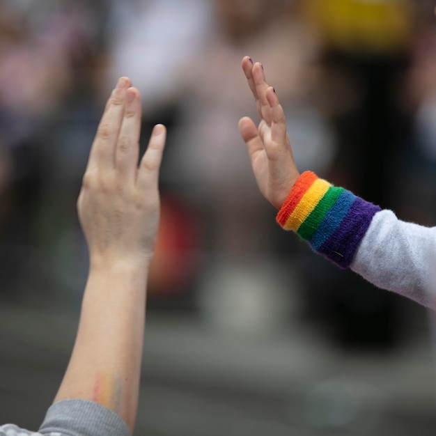 Een kind dat een polsbandje met een gay pride-vlag draagt, geeft een high five aan een volwassene