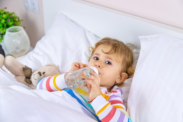 Een kind drinkt uit een fles in bed Selectieve focus