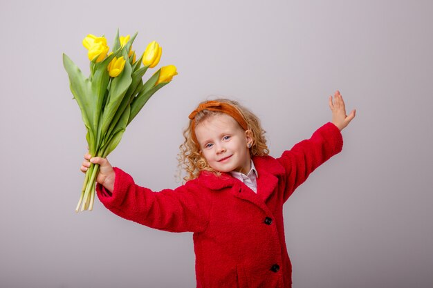 Een kind een blond meisje met een boeket gele tulpen