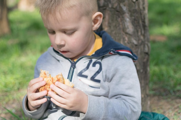 Een kind eet een broodje in het park