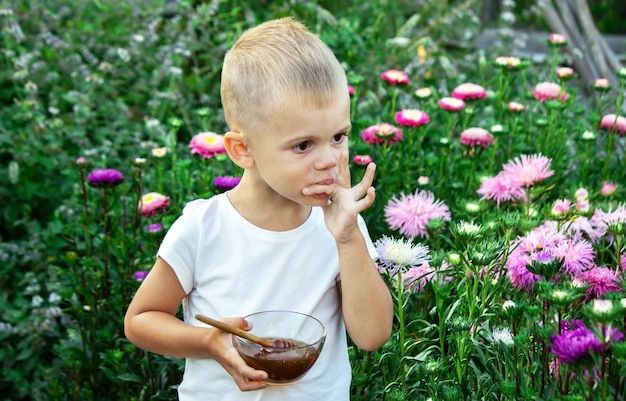 Een kind eet honing in een bloementuin. Selectieve focus
