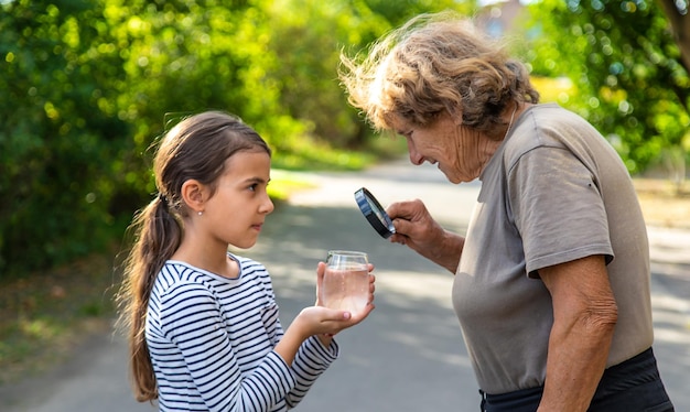 Een kind en grootmoeder onderzoeken het water met een vergrootglas Selectieve focus