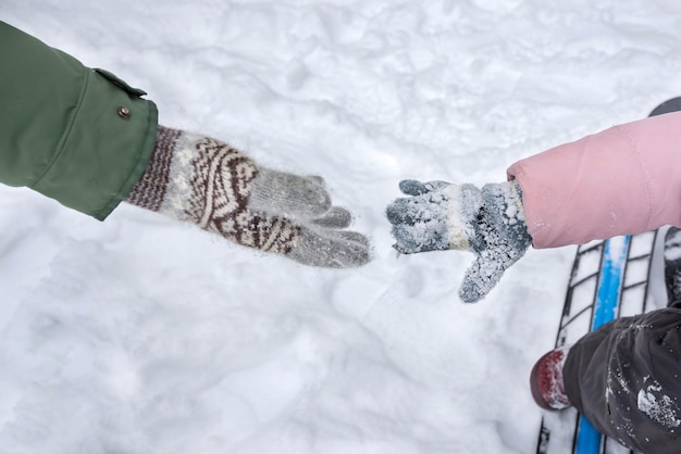 Een kind en ouders dienen winterhandschoenen in die naar elkaar reiken waar de handen eerder naar reiken