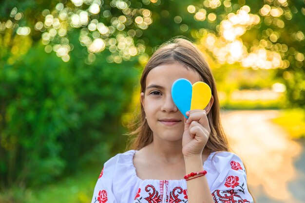 Foto een kind houdt een hart van de oekraïense vlag vast selectieve focus