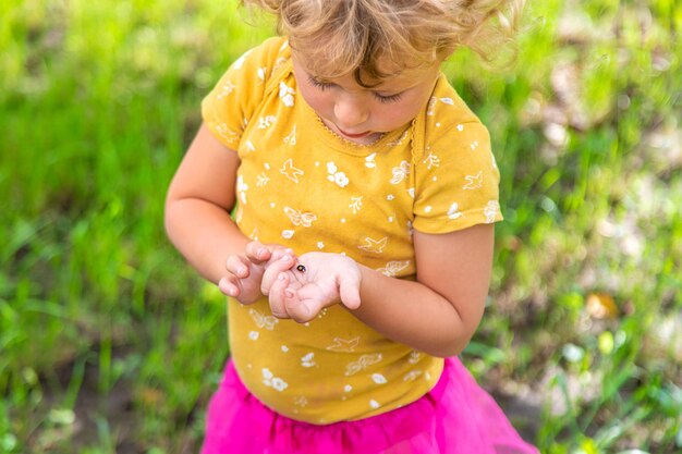 Foto een kind houdt een lieveheersbeestje op haar hand selectieve focus natuur