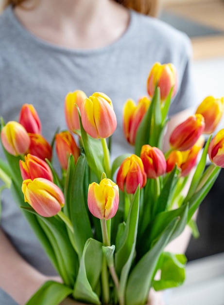 Een kind houdt een mooi boeket rode en gele tulpen vast in het concept van de lentetijd in close-up