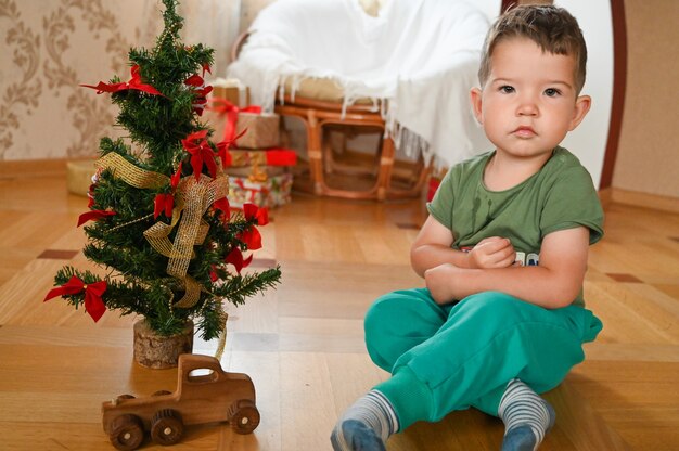 Een kind in de buurt van de kerstboom opent een geschenk. Hoge kwaliteit foto