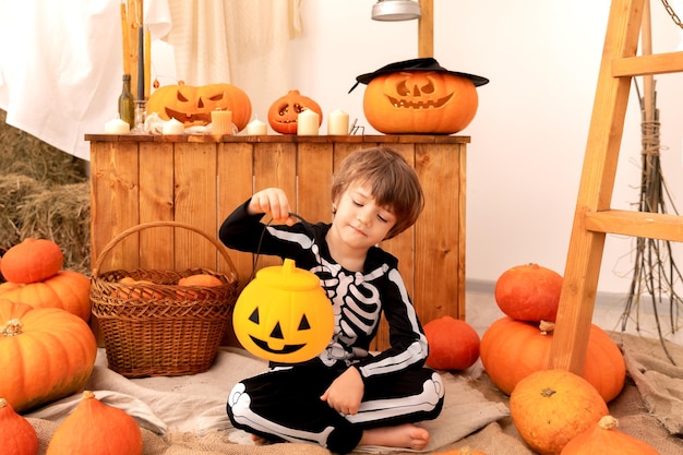 een kind in een halloween kostuum zit met een pompoen pot vol snoep van hoge kwaliteit foto
