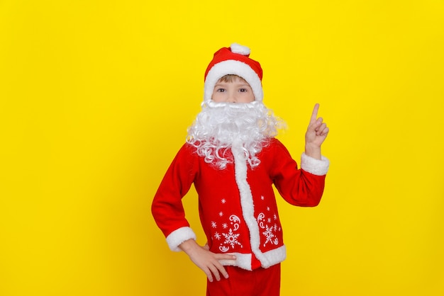 Een kind in kerstmankleren en een kunstmatige baard maakt een handgebaar wijsvinger omhoog