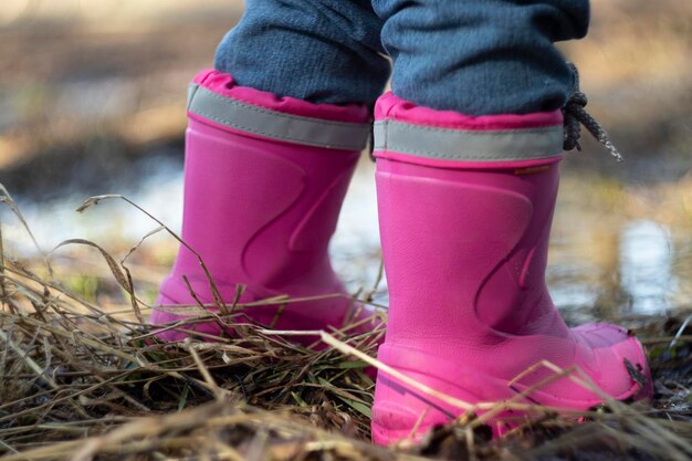 Een kind in rubberen kinderlaarzen staat op het gras