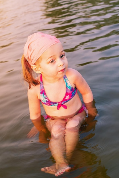 Een kind in zwempak in de zomer op vakantie Een klein meisje zwemt in de rivier