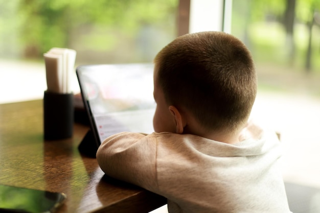 Een kind kijkt tekenfilms in een café Jongen met tablet in een restaurant