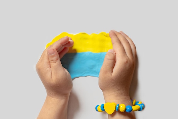 Een kind maakt de vlag van Oekraïne deeg Kind met plasticine in de kleuren van de vlag van Oekraïne in handen Creativiteit voor kinderen DIY vakantie handwerk en knutselgereedschap Bid voor Oekraïne