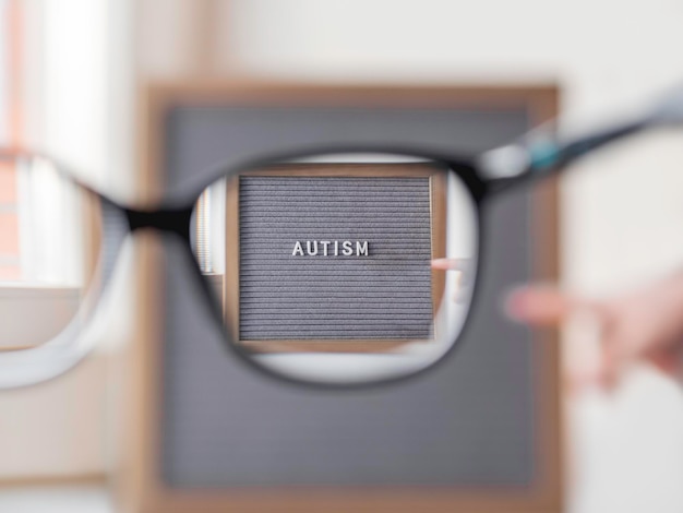 Foto een kind met autisme wijst op een briefbord en kijkt door een bril naar een medische diagnose.