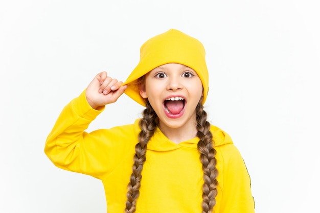 Een kind met een hoed en een geel trainingspak Close-upportret van een glimlachend klein meisje