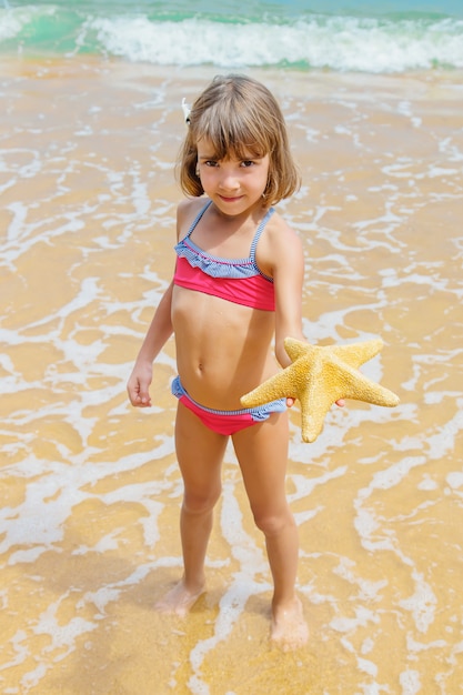 Een kind met een zeester in zijn handen op het strand