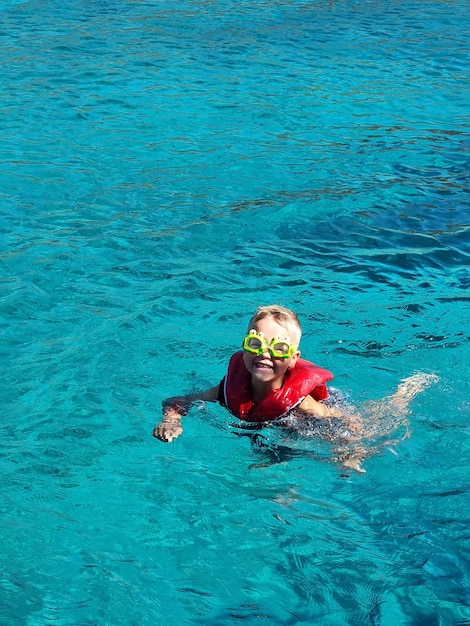 Een kind met een zwembril en een jambad in de zee