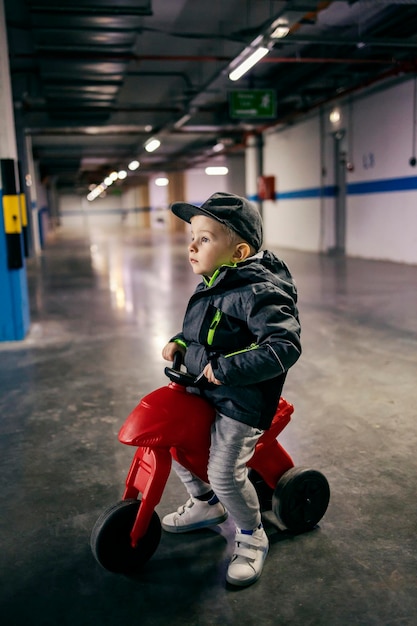 Een kind op een driewieler speelt verkeer in een ondergrondse garage