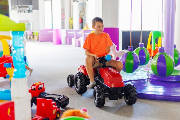 Een kind rijdt op een speelgoed pedaal auto in een speelcentrum voor kinderen