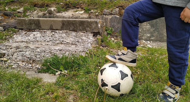 Foto een kind speelt een bal in de tuin op groen gras, de jongen trapt de bal met zijn voet