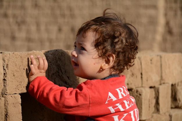 Een kind speelt met een bakstenen muur