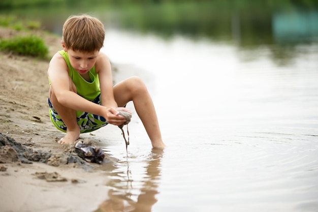 Een kind speelt met het zand aan de kust Een jongen aan het water op het meer