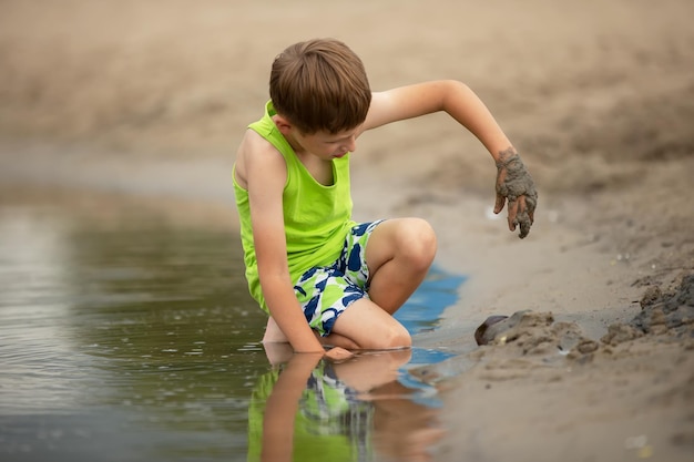 Een kind speelt met zand aan de oevers van de rivier