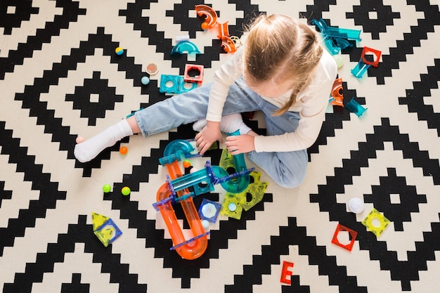 Een kind speelt thuis of op de kleuterschool met een magnetische constructeur op een tapijt Een speelgoedhuis bouwen uit blokken Bovenaanzicht