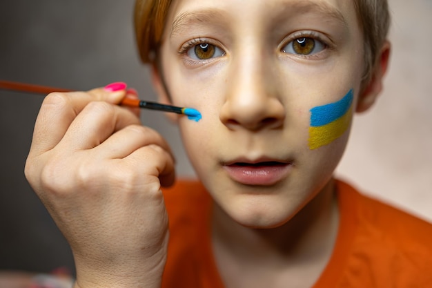 Een kind tegen oorlog een jongen met een geschilderde vlag van Oekraïne op zijn wangen