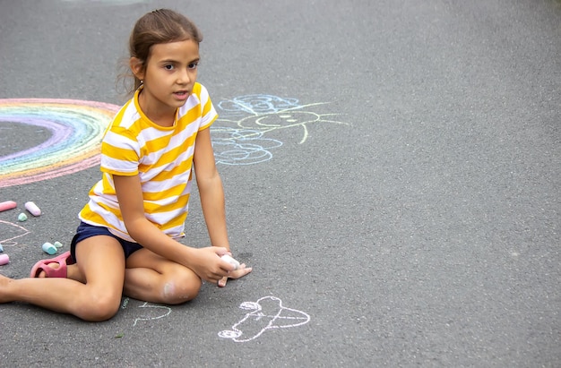 Een kind tekent een regenboog op het asfalt selectieve focus