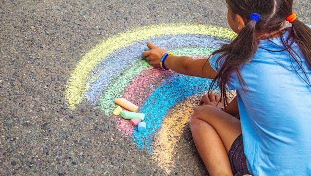 Een kind tekent een regenboog op het asfalt selectieve focus