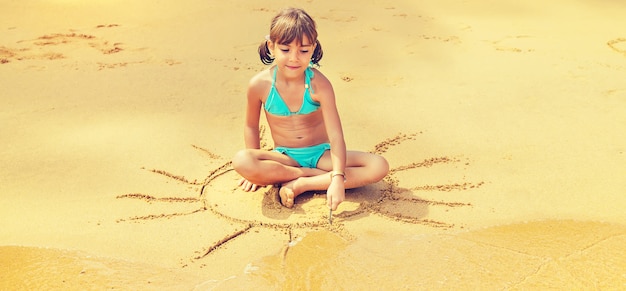 Een kind trekt een zon op het strand