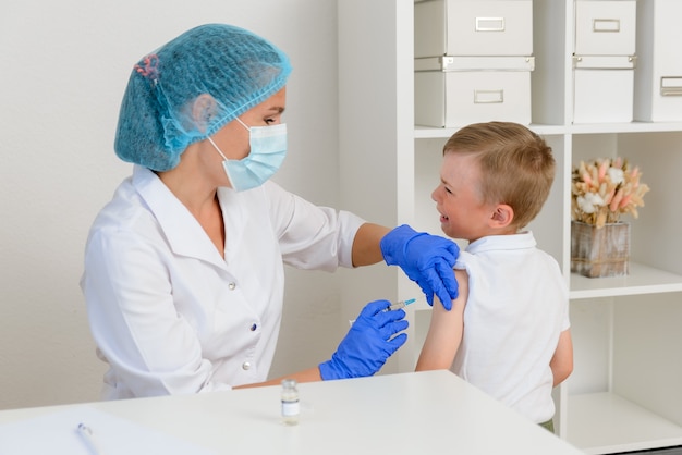 Een kinderarts of verpleegkundige houdt een spuit vast om een ziek kind te vaccineren met een injectie