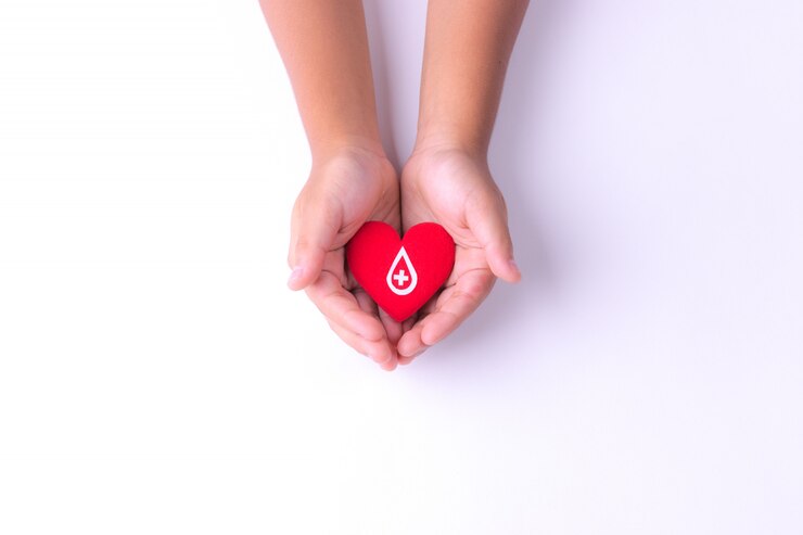 Een kindhanden die rood hart voor bloedschenking houden