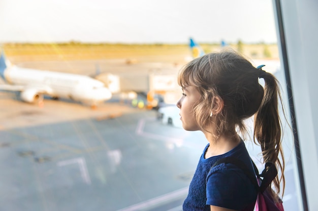 Een kindmeisje op de luchthaven kijkt naar de vliegtuigen