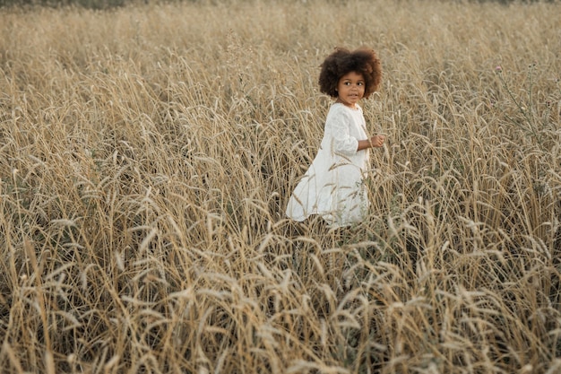 Foto een klein afrikaans meisje loopt door een zomerveld.