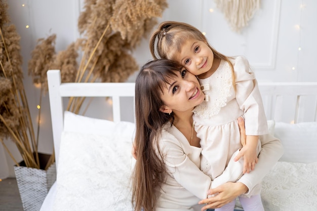 Een klein babymeisje met haar moeder knuffelen en zoenen thuis op het bed lifestyle gelukkig gezin en moederschap internationale vrouwendag of moederdag hoogwaardige fotografie