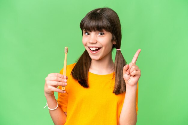 Een klein blank meisje dat tanden poetst over een geïsoleerde achtergrond die een geweldig idee benadrukt